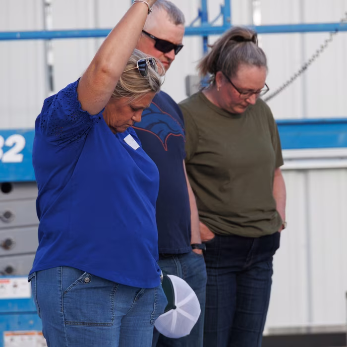 Church members praying together near construction equipment